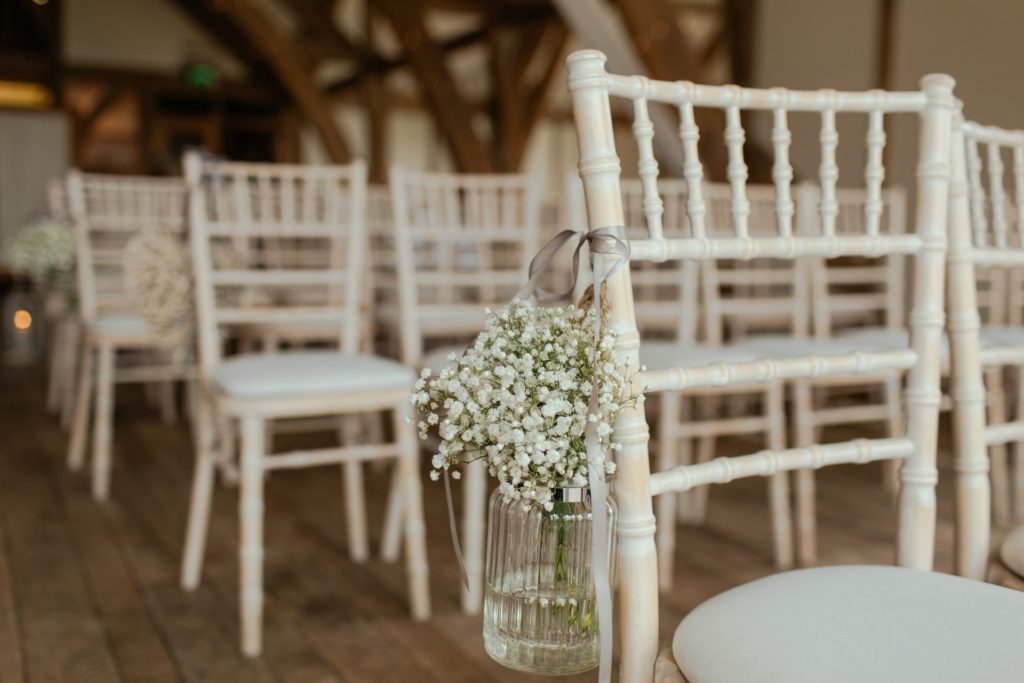 Chaises blanches décorée avec un bouquet de gypsophile pour un mariage.