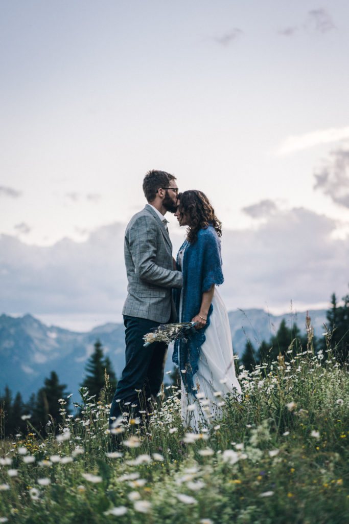 Couple de mariés dans une prairie en montagne