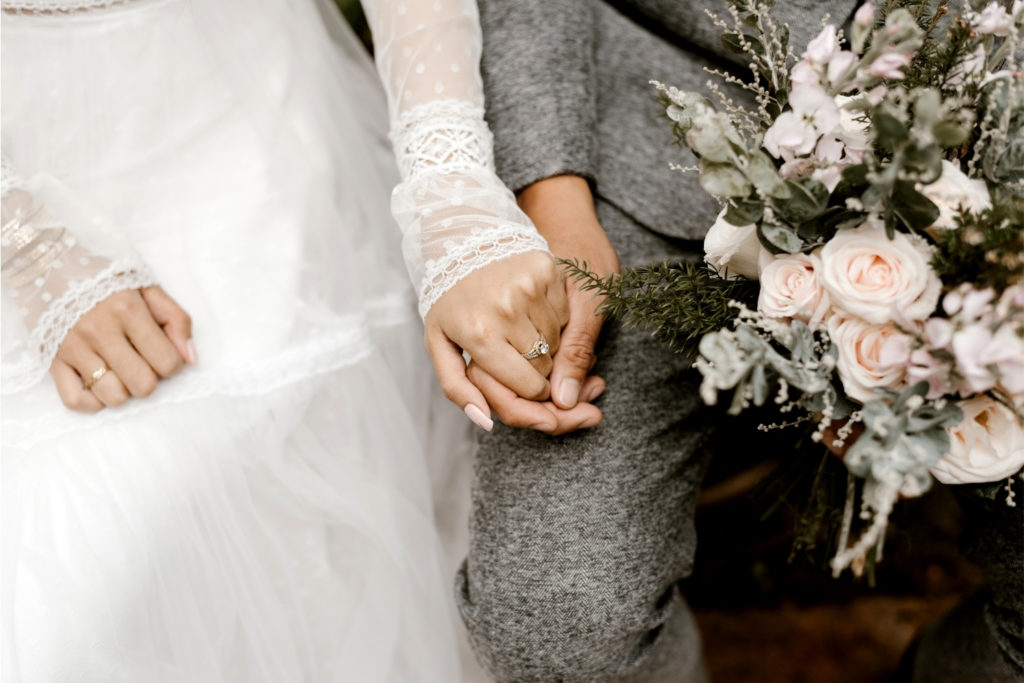 Gros plan sur le bouquet et les mariés qui se tiennent la main
