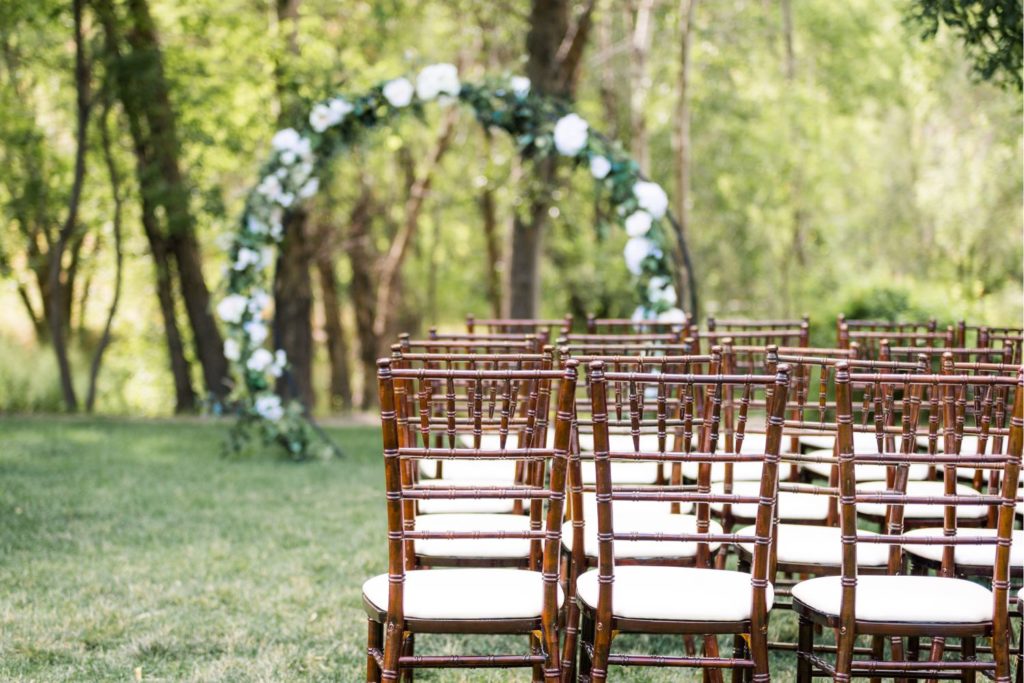 Chaises en bois alignées avec une arche de mariage en arrière plan