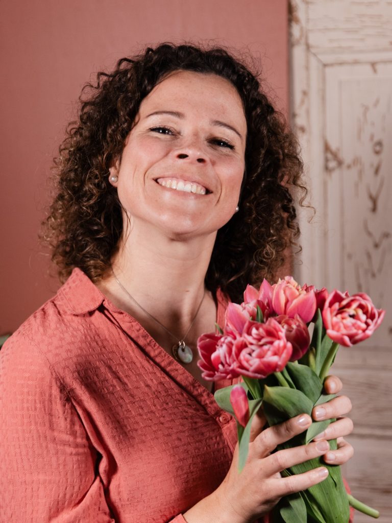 Jeune femme en chemise rose tenant un bouquet de fleur