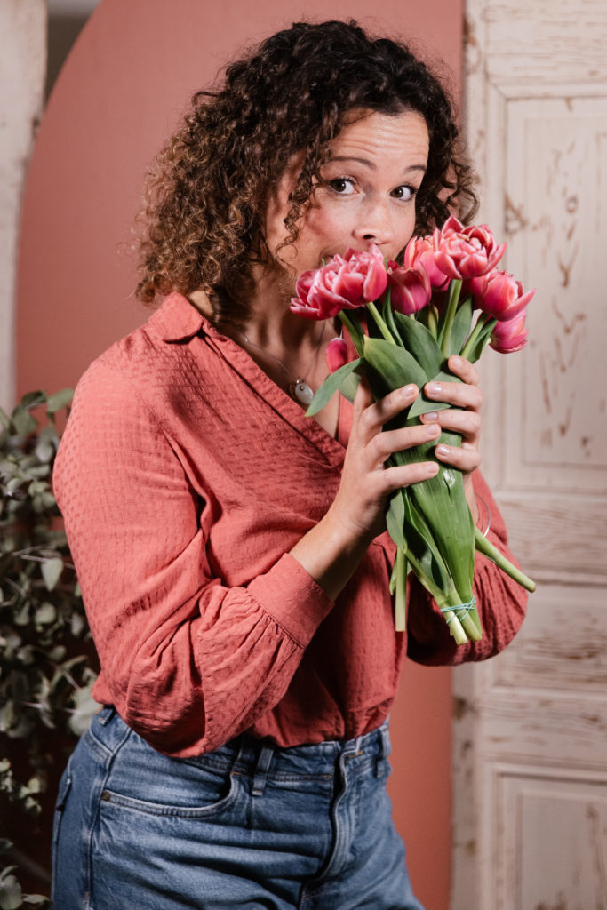 Femme frisée qui sent un bouquet de fleurs roses